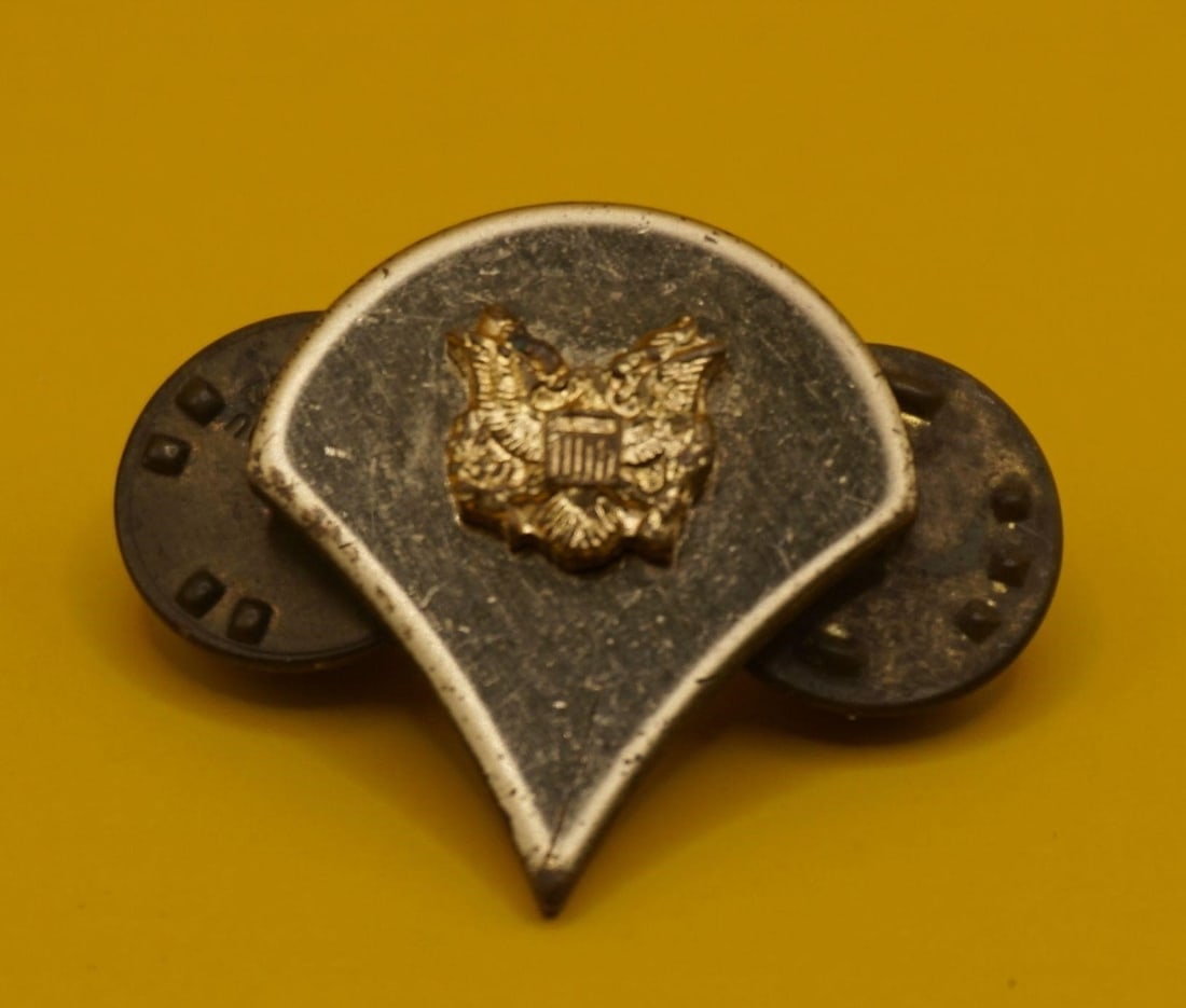 Vintage US Army Specialist E4 Rank Insignia Pin: This is a vintage US Army Specialist (E-4) rank insignia pin. It features an eagle device, which is the symbol for the Specialist rank in the US Army. The insignia is typically worn on the collars of