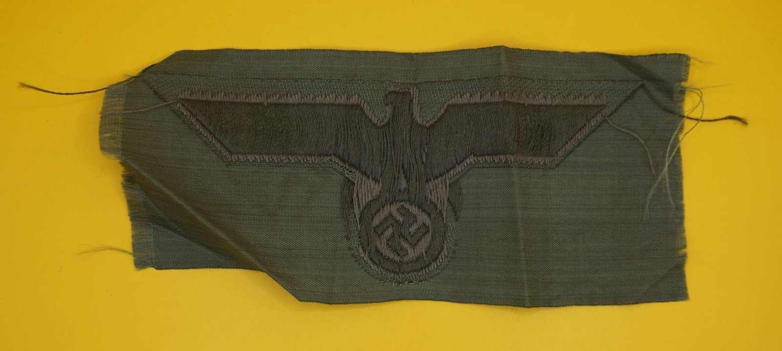 WWII German Heer M39 Woven Breast Eagle: This is a World War II German Army (Heer) M39 pattern machine-woven breast eagle patch. It is an insignia intended for wear on the combat field blouse. The eagle design is woven in pale grey rayon thr