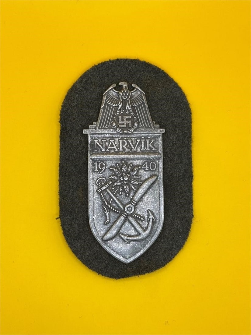 WWII Narvik Campaign Shield - Heer: Awarded to German Heer troops in the 1940 Narvik campaign, this zinc shield features an eagle over "Narvik," with edelweiss, propeller, and anchor symbols. Includes original green cloth backing and