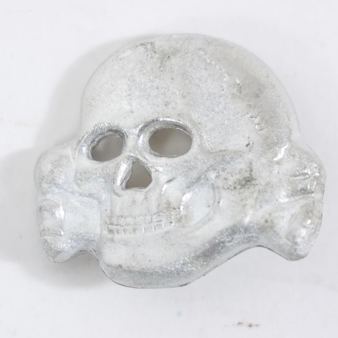 Vintage Totenkopf Skull Cap Insignia: The object in the image is a vintage metal cap insignia, known as a "Totenkopf" (death's head).