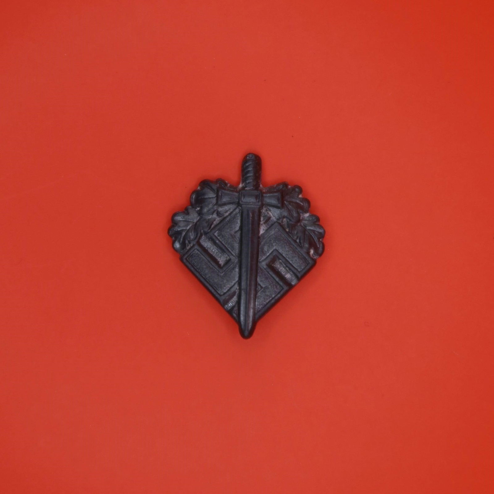 NSKOV Donation Pin (WWII Era): A small aluminum lapel pin issued by the NSKOV, an organization that supported wounded German veterans. The front shows a sword laid over a swastika with oak leaves around the upper portion. The