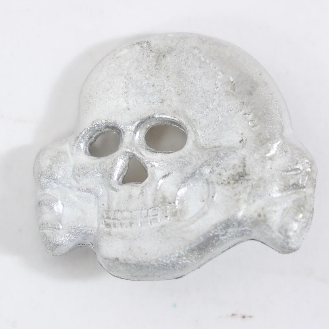 Vintage Totenkopf Skull Cap Insignia: The object in the image is a vintage metal cap insignia, known as a "Totenkopf" (death's head).