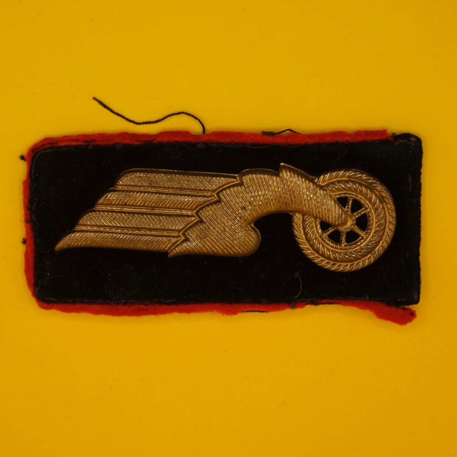 German Reichsbahn Collar Tab (First Pattern): Original German Reichsbahn first pattern collar tab (circa 1933), black velvet with red wool piping, stamped alloy winged wheel emblem, tan buckram backing.