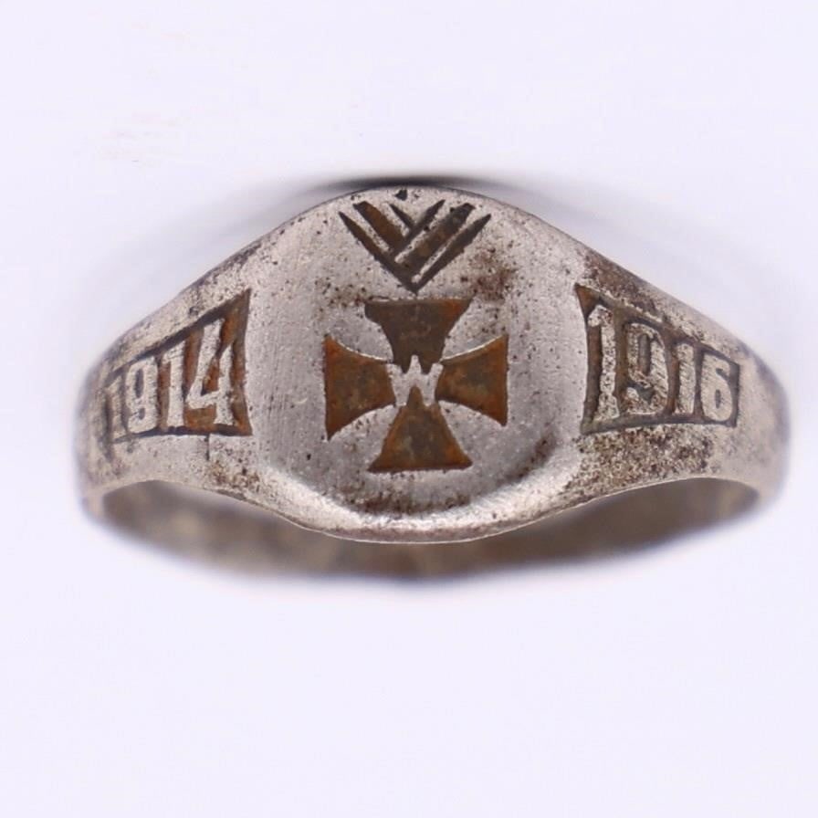 WWI German Silver Ring 1914-1916: WWI German Silver Ring featuring engraved dates "1914" and "1916" on the shoulders and a central cross emblem with crown-like detailing above it. It shows natural age wear and patina but remains