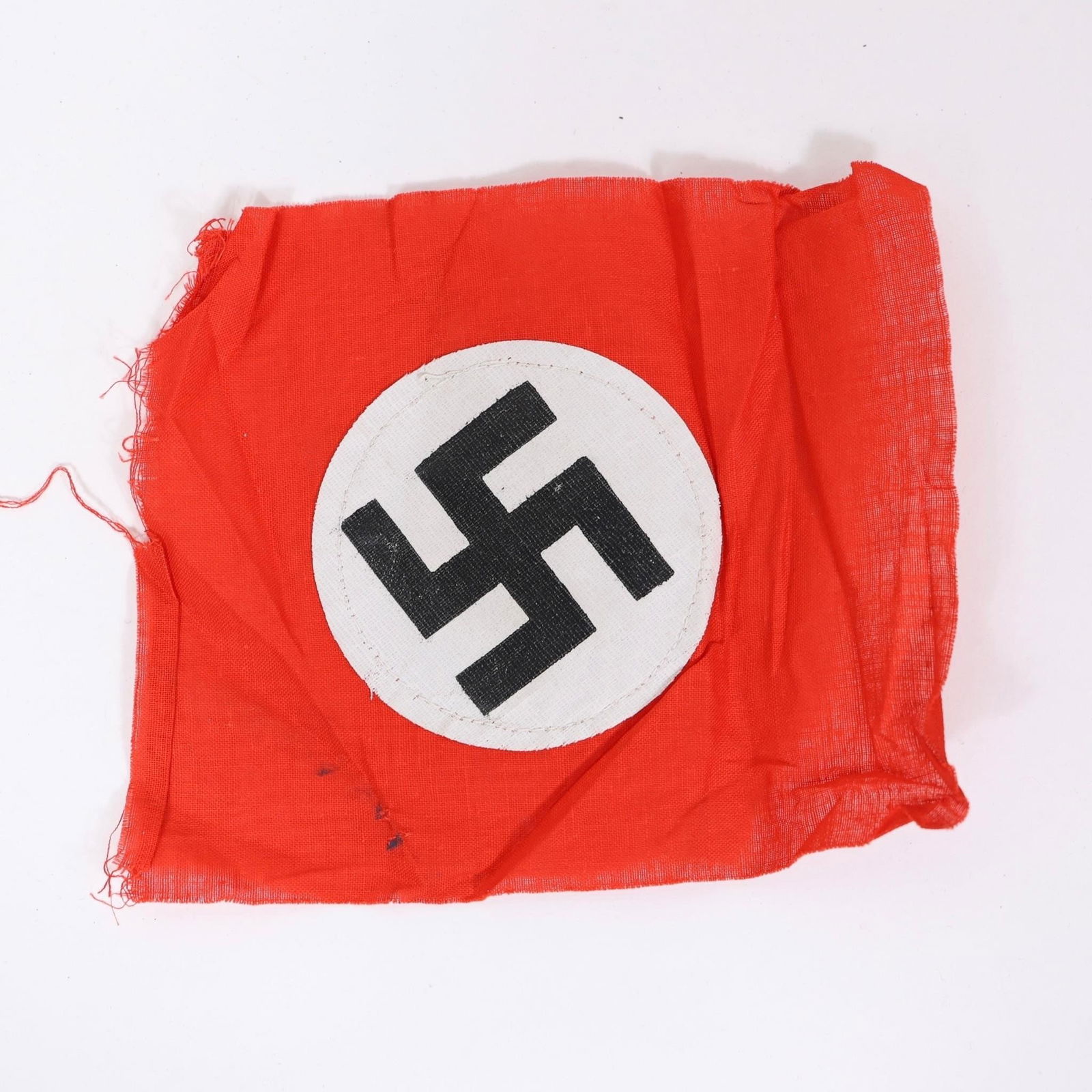WWll German Party Armband: Two sided red cloth armband featuring a white circular roundel with a black angled swastika at the center. Constructed of woven fabric with finished edges. Measures approximately 7.5 × 6.7 inches.