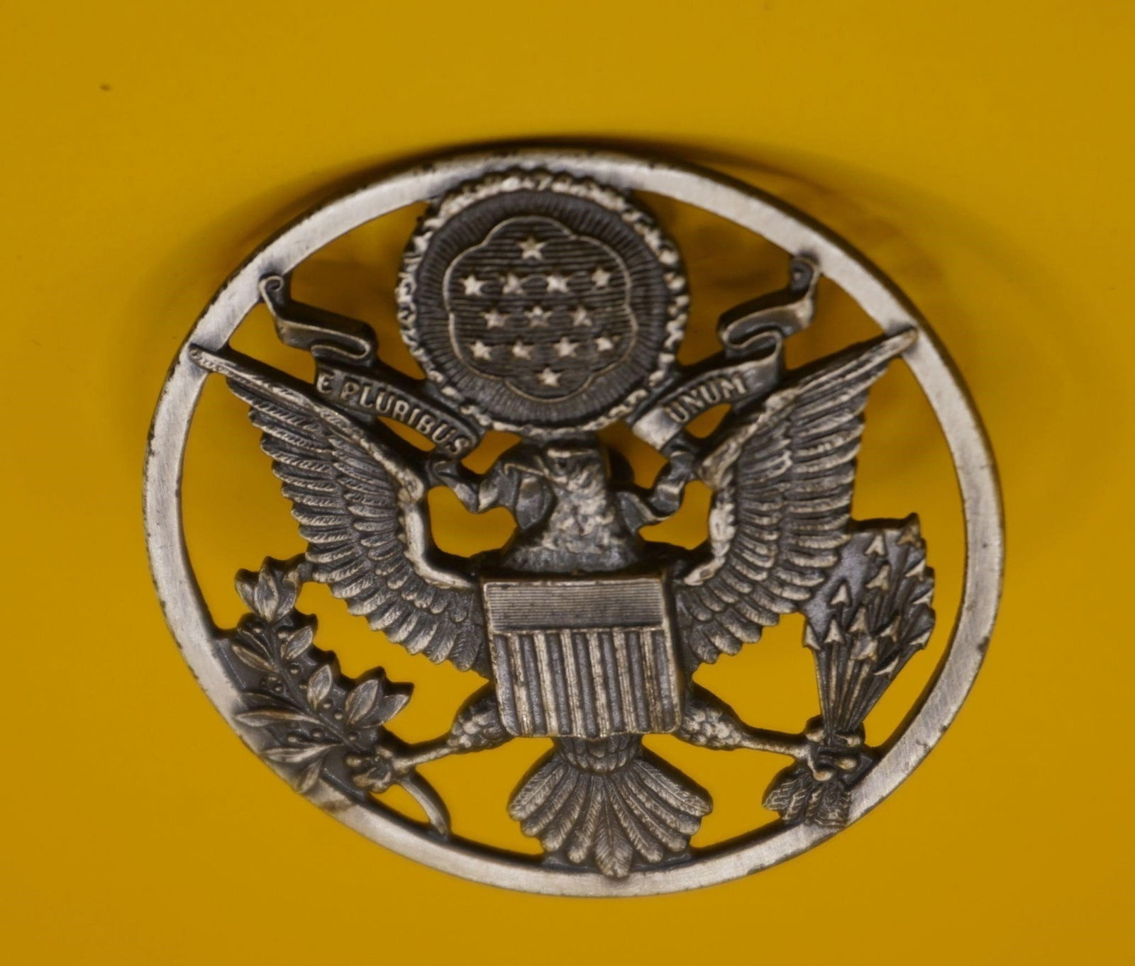 WWII USAF Enlisted Male Service Cap Device: This is a United States Air Force (USAF) enlisted male service cap device. It features the United States Coat of Arms enclosed within a ring. The ring distinguishes it from the officer's version,
