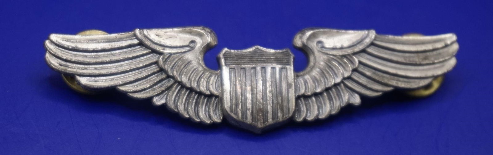 WWII US Army Air Forces Pilot's Wing Badge: This is a U.S. Army Air Forces pilot's wing badge, from the World War II era. The insignia measures approximately 3 inches across. It is a replica of the style worn by U.S. Air Force pilots since WWII
