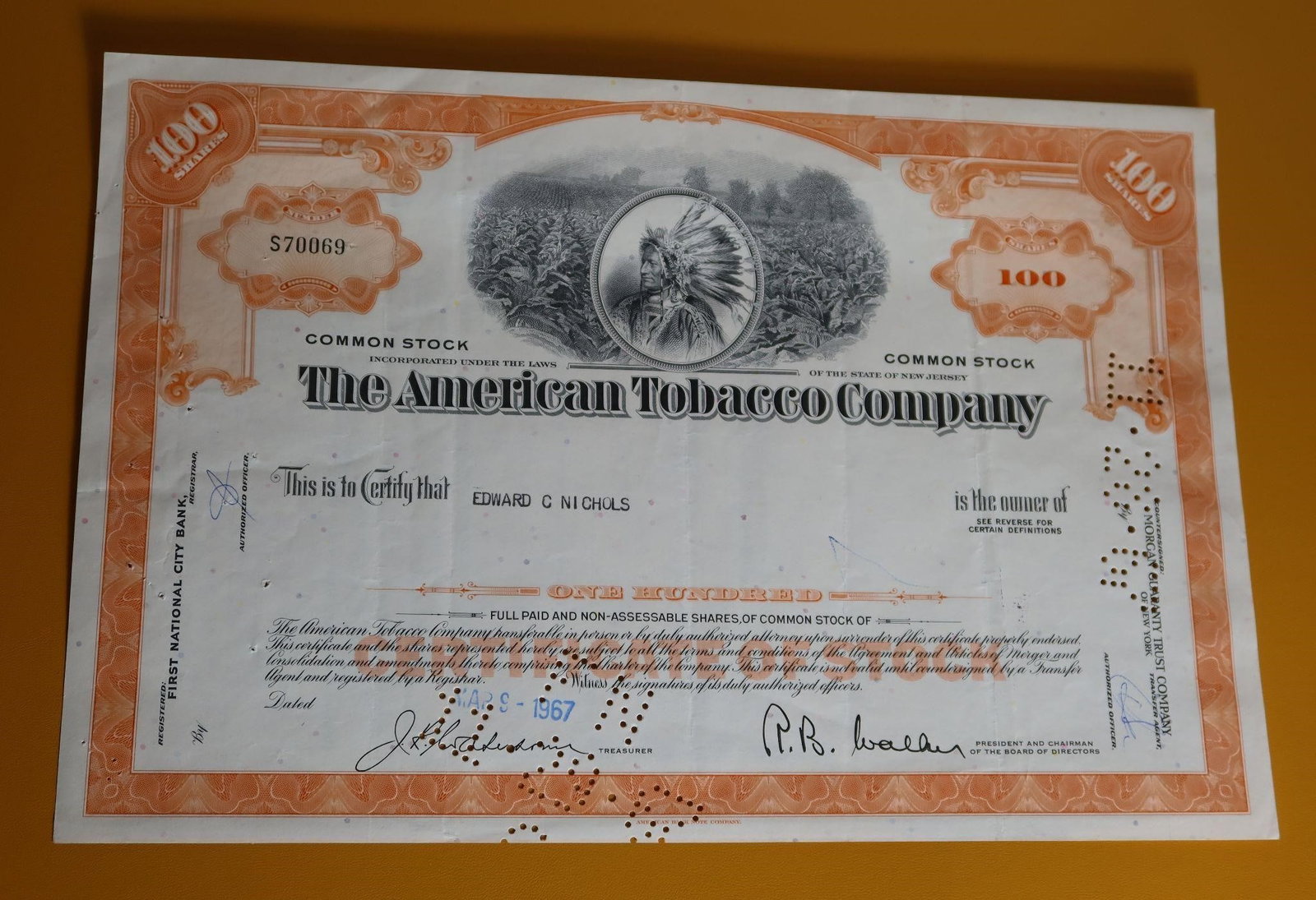 Vintage American Tobacco Company Stock Certificate: A vintage American Tobacco Company stock certificate. It is a historic document, dated April 28, 1967, and issued to Edward G. Nichols for one hundred shares of common stock. The certificate is consid