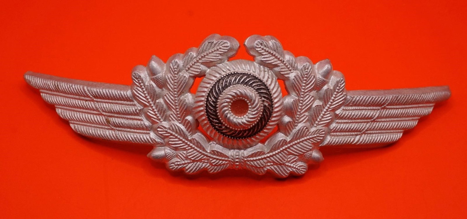 WWII German Luftwaffe Visor Cap Wreath & Cockade: Original WWII Luftwaffe visor cap wreath and tri-color cockade, silver-washed aluminum, detailed winged oak-leaf design, prongs intact, good used condition.