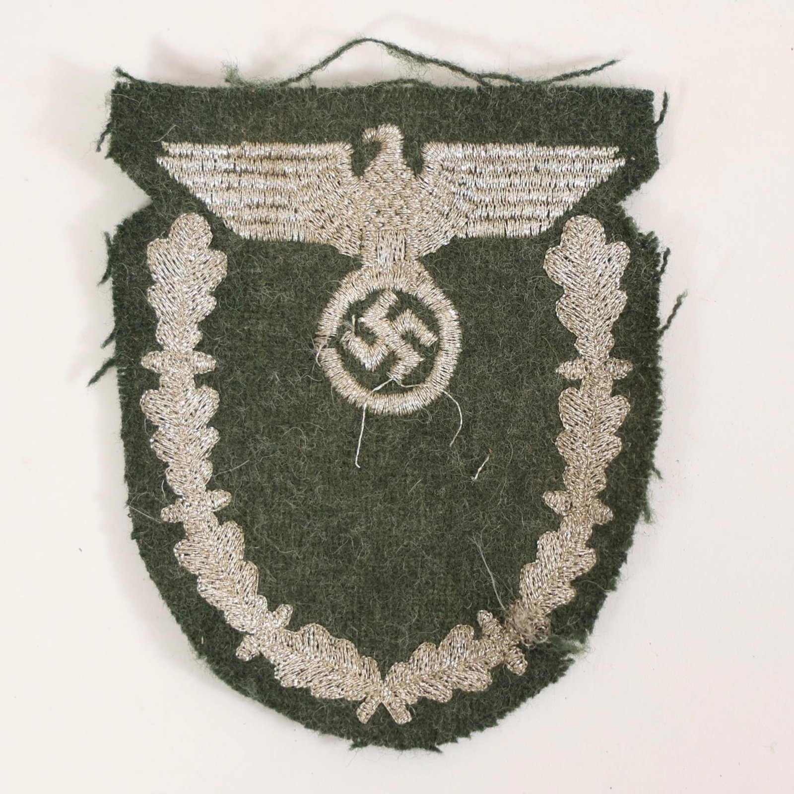 WWII German Bullion Sleeve Eagle Insignia: World War II German cloth sleeve insignia (Ärmeladler), featuring finely detailed silver bullion embroidery of the national eagle clutching a swastika, framed by oak leaf wreath on green wool