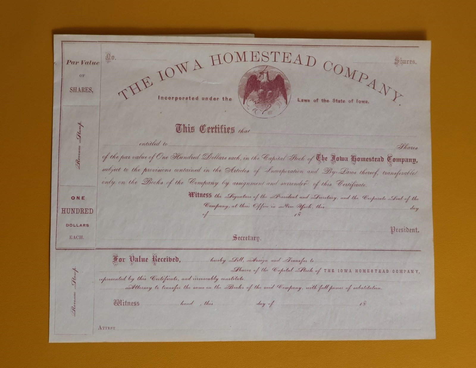 Antique Iowa Homestead Co. Stock Certificate: An antique stock certificate for The Iowa Homestead Company. It is incorporated under the laws of the State of Iowa. Each share has a par value of One Hundred Dollars. The certificate is transferable