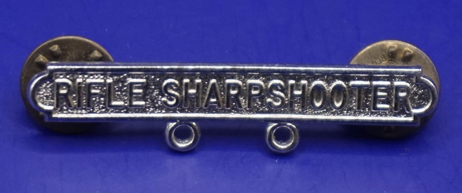 WWII Rifle Sharpshooter qualification Badge: This is a military marksmanship qualification badge for a Rifle Sharpshooter. It is awarded to military personnel who achieve a specific level of proficiency with a service rifle. The qualification