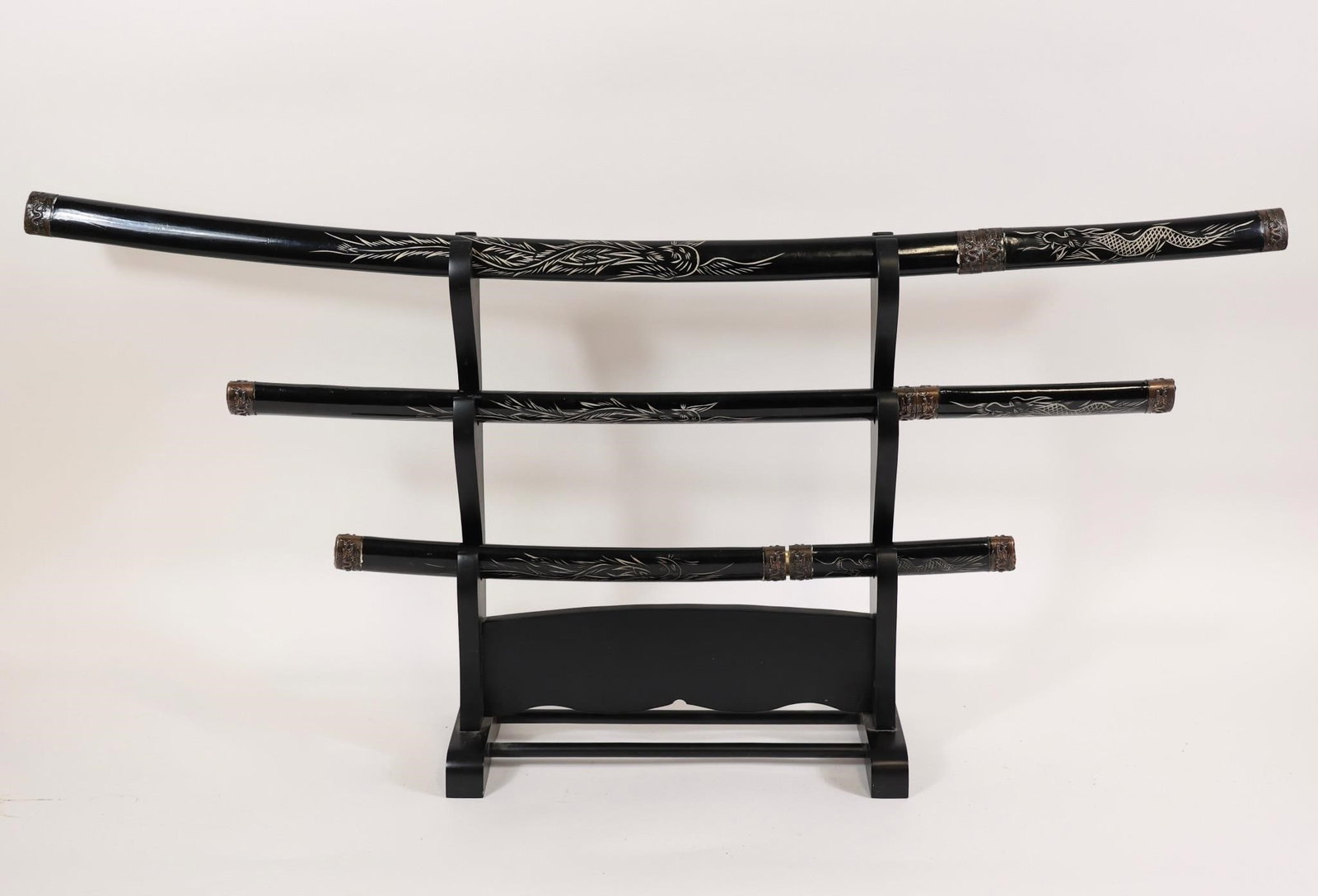 Set of 3 Katana Swords w/ Stand/Decor: Three-piece Japanese-style sword set on black stand, including katana, wakizashi, and tanto. Black scabbards with dragon motifs and decorative fittings. Clean condition with light wear.Katana: OL