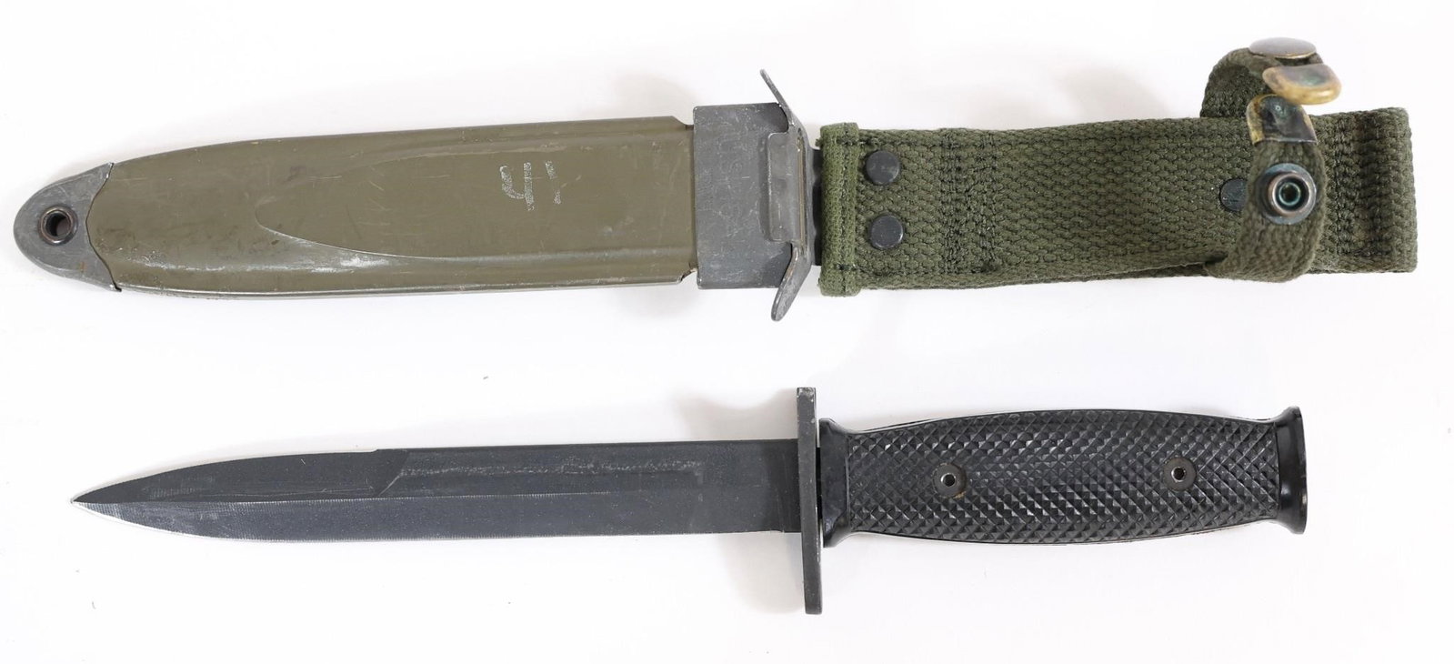 Spanish Military Bayonet w/ Scabbard: Spanish military bayonet featuring a fullered blade, steel guard, and black checkered grip with screw fasteners. Includes green metal scabbard with canvas frog attachment. Approximate measurements:
