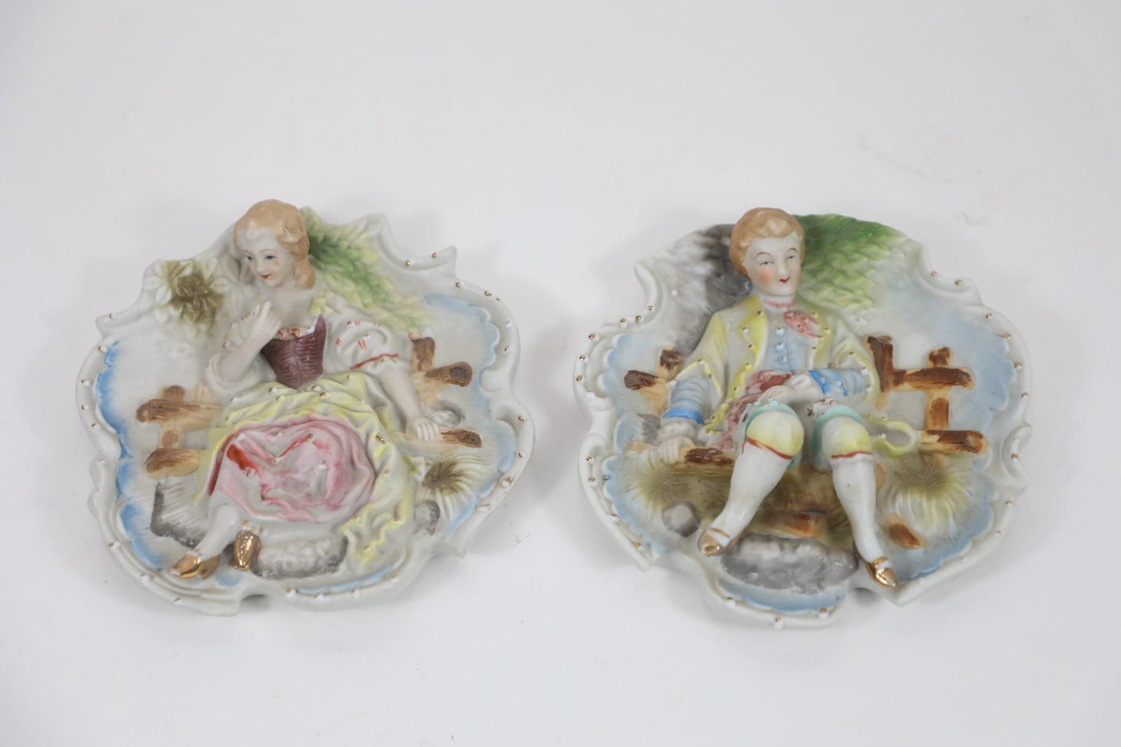 Pair of Vintage Hand-Painted Porcelain Plaques: Hand painted, Made in Japan These two images appear to show a pair of decorative porcelain plaques or wall pockets, featuring a man and a woman in 18th-century style dress. Here is a detailed descript