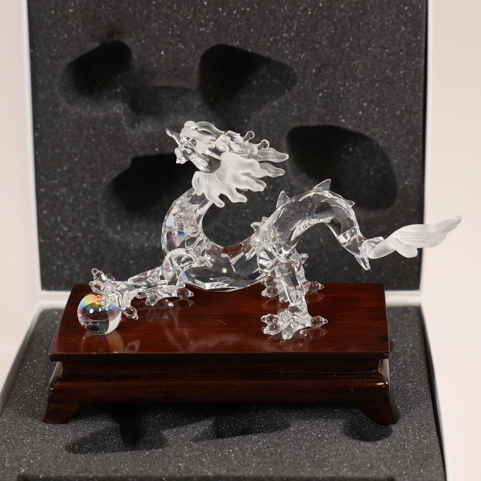 Swarovski Crystal Dragon Figurine: This collectible item is a Swarovski Crystal Dragon figurine, featuring a clear crystal body on a wooden base.