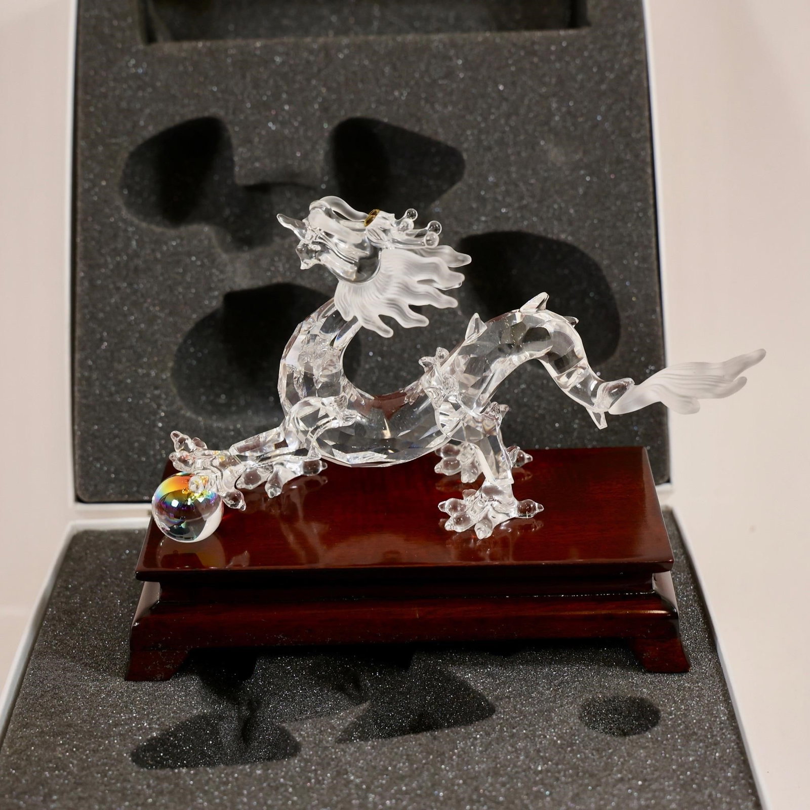 Swarovski Crystal Dragon Figurine: This collectible item is a Swarovski Crystal Dragon figurine, featuring a clear crystal body on a wooden base.