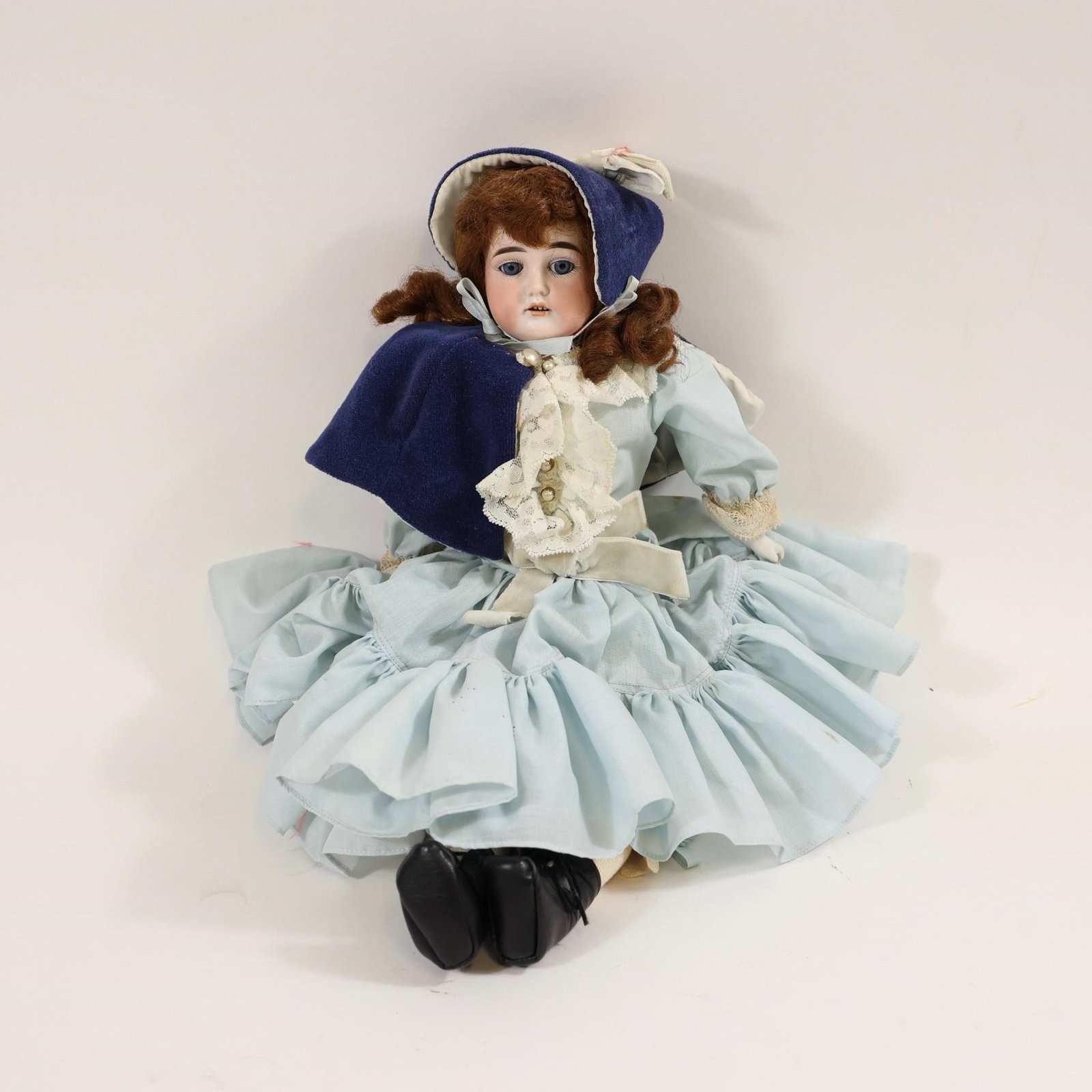 Antique German Bisque Doll 1896: Collectible antique German bisque doll marked "1896," featuring a bisque porcelain head with realistic matte finish, blue glass eyes, and a brown mohair wig; dressed in a period-style light blue ruffl