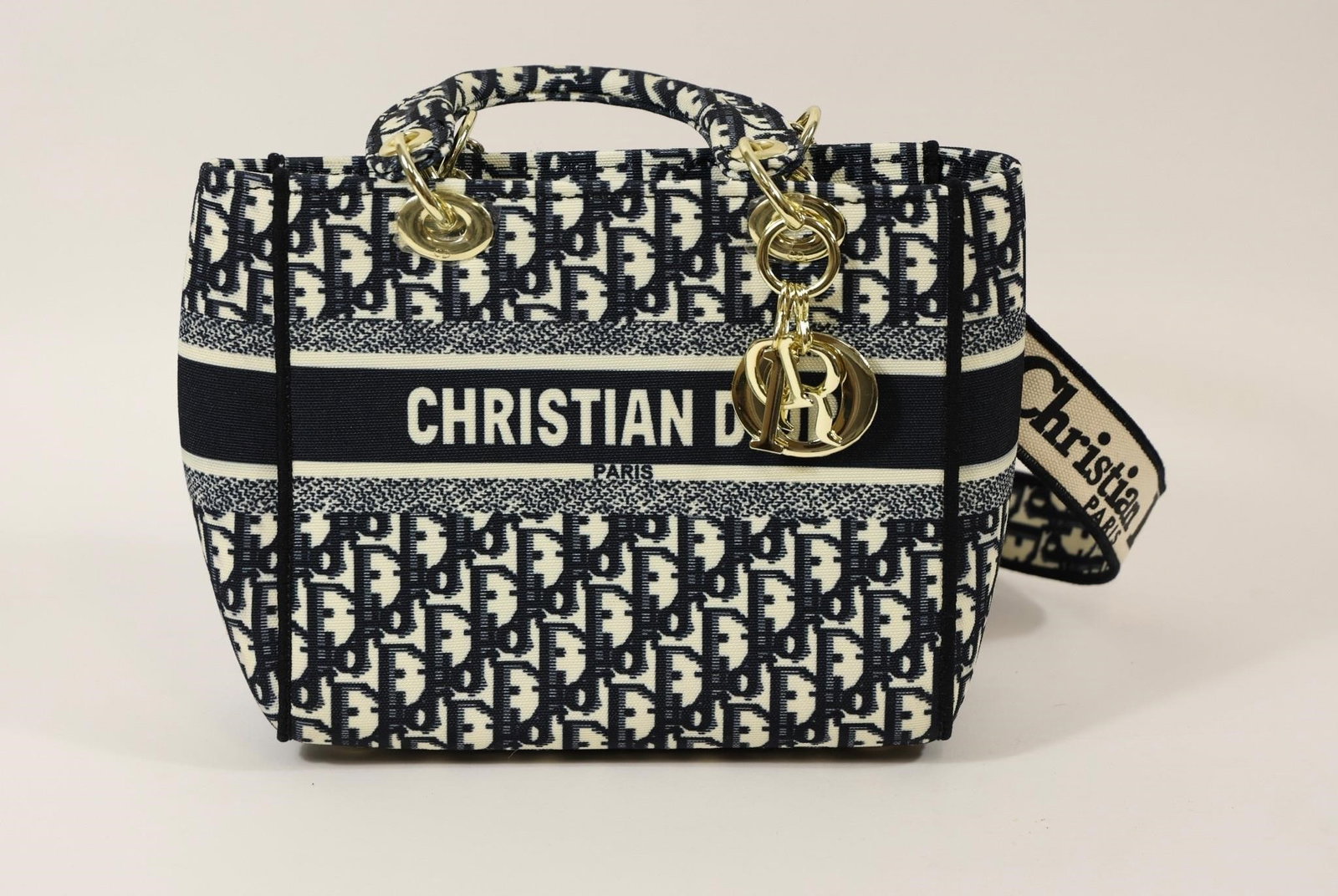 Christian Dior Oblique Lady Dior Canvas Handbag: Elegant Christian Dior Lady Dior handbag featuring the iconic navy blue and cream Oblique monogram canvas. Includes gold-tone hardware, signature Dior charm, structured top handles, and a detachable