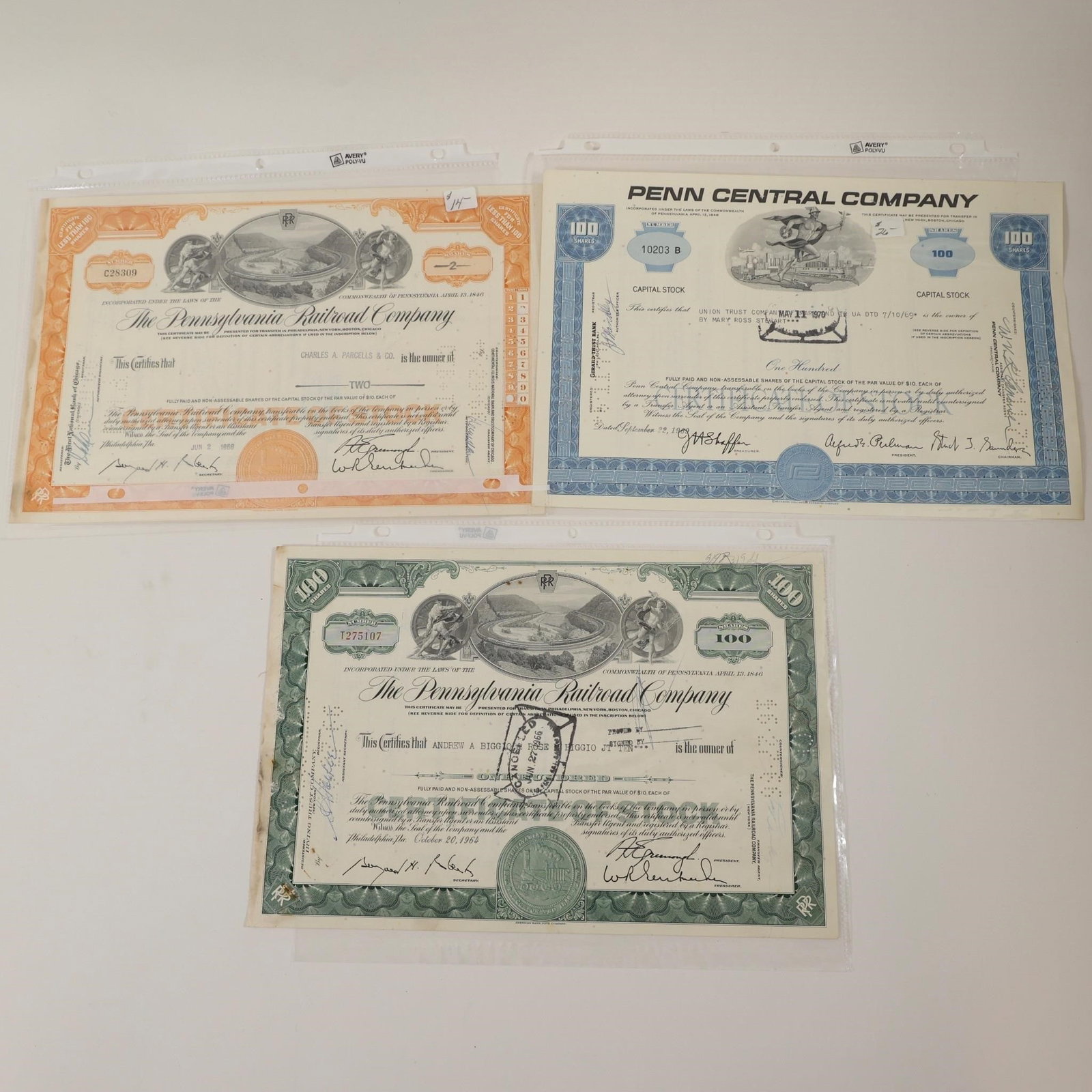 Pennsylvania Railroad & Penn Central Stocks: Group of three vintage railroad stock certificates including Pennsylvania Railroad Company and Penn Central Company examples. Features engraved artwork, company seals, cancellation markings, and