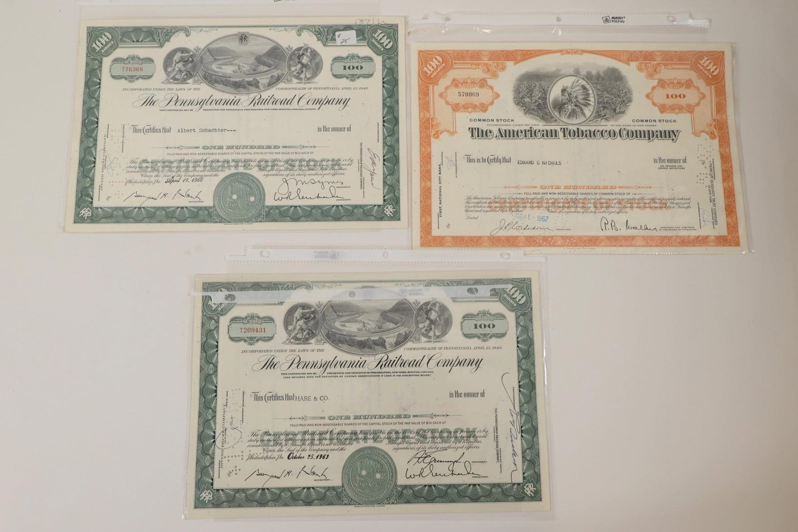 American Tobacco & Railroad Stocks: Group of three vintage stock certificates including two Pennsylvania Railroad Company certificates and one American Tobacco Company common stock certificate. Features engraved artwork, company seals,