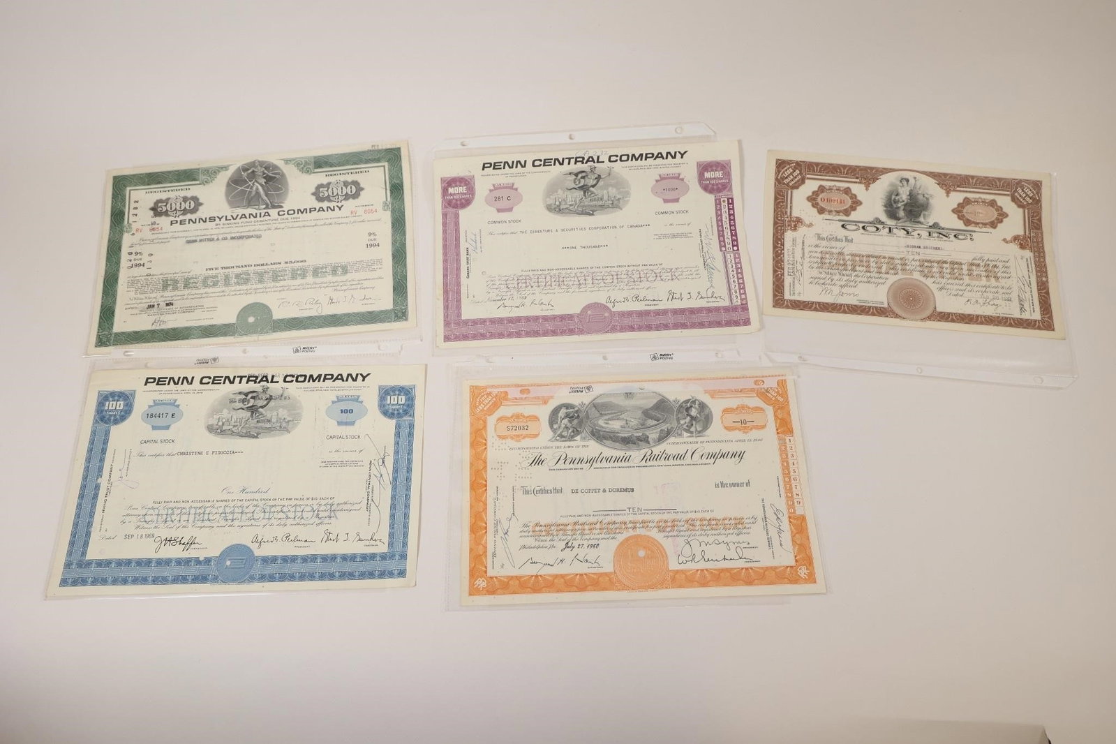 Railroad & Corporate Stock Certificates: Collection of five vintage stock certificates including Pennsylvania Company, Penn Central Company (2), Pennsylvania Railroad Company, and Colt, Inc. Features engraved artwork, company seals,