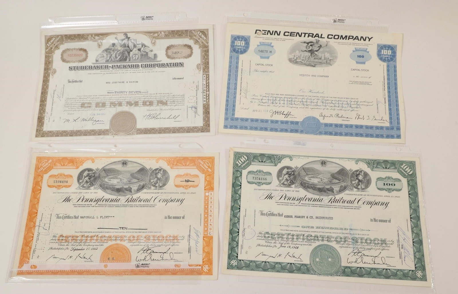 Vintage Railroad & Corporate Stock Certificates: Group of four vintage stock certificates including Studebaker-Packard Corporation, Penn Central Company, and two Pennsylvania Railroad Company certificates. Features engraved vignettes, corporate