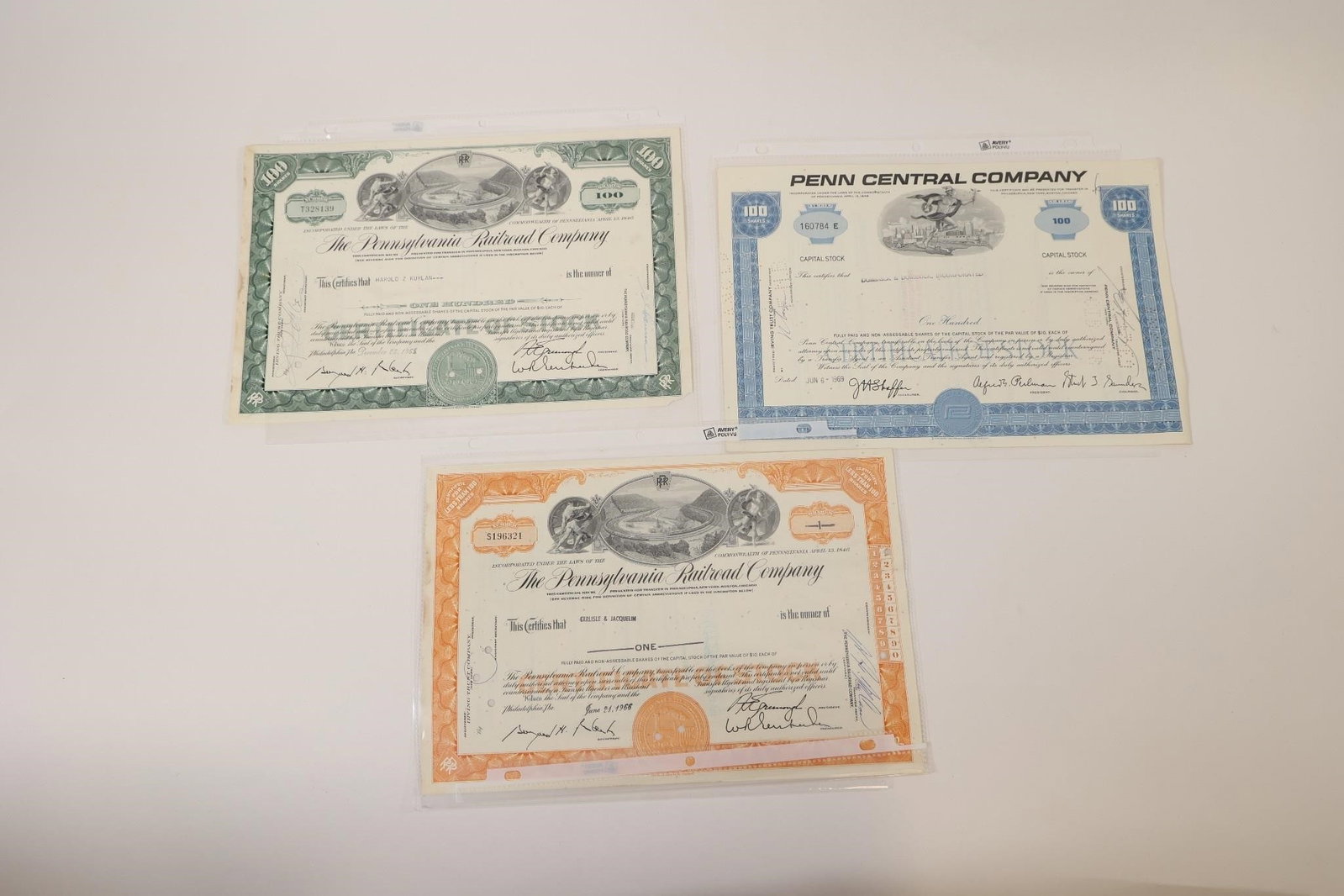 Pennsylvania Railroad & Penn Central Certificates: Group of three vintage stock certificates including two Pennsylvania Railroad Company certificates and one Penn Central Company certificate. Features engraved railroad-themed artwork, corporate