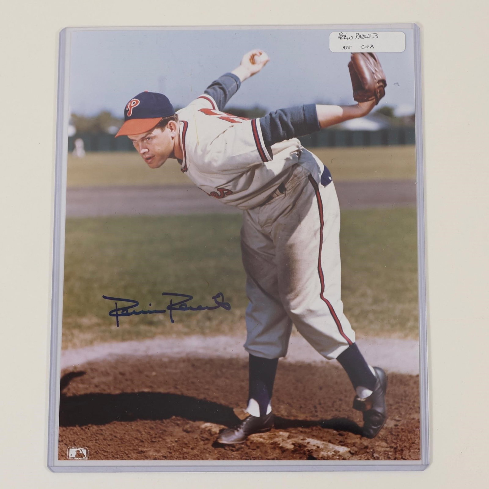 Robin Roberts Signed Philadelphia Phillies Photo: Autographed color photograph featuring Hall of Fame pitcher Robin Roberts in a Philadelphia Phillies uniform. Signed in blue ink across the lower portion of the image and presented in a protective