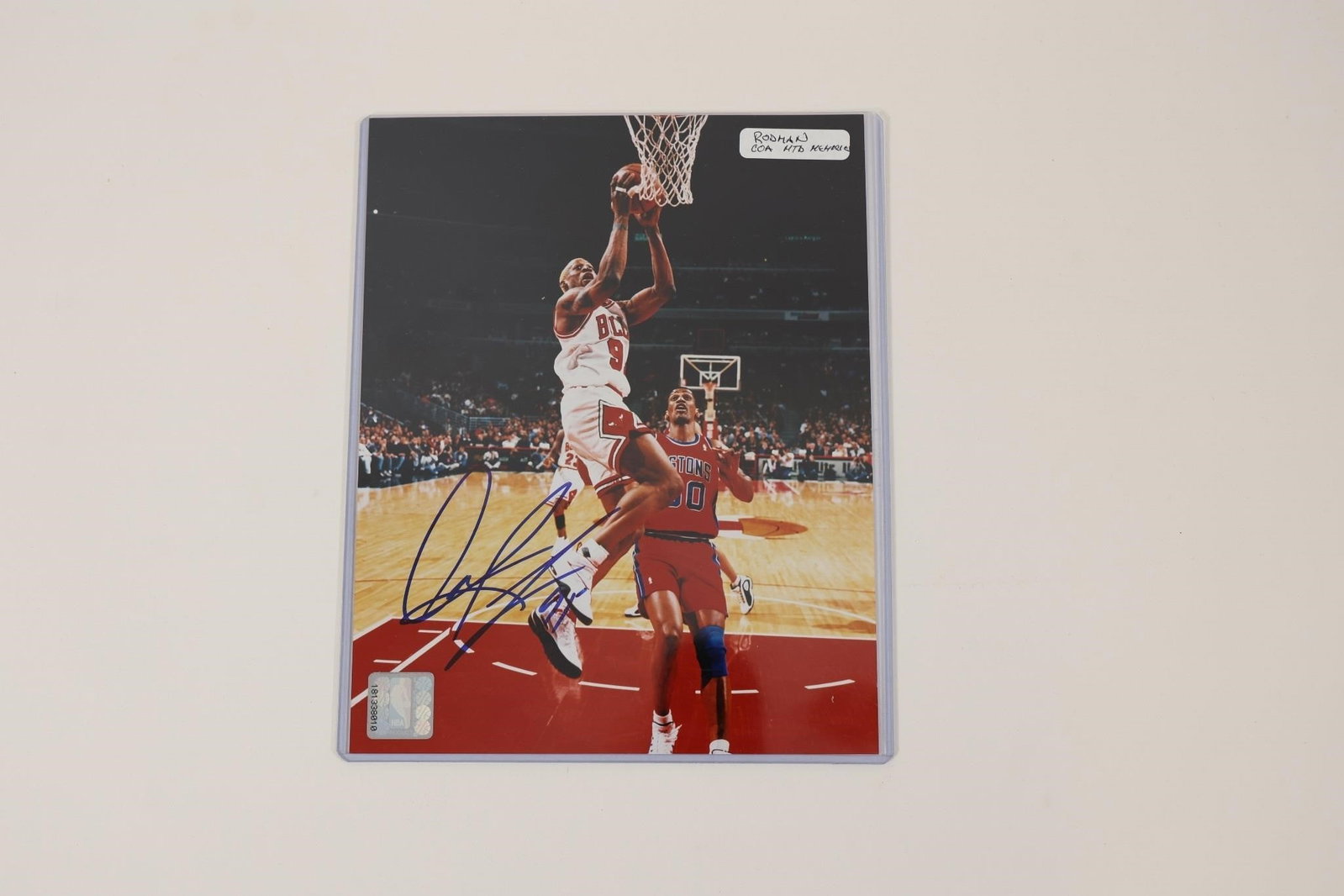 Dennis Rodman Signed Chicago Bulls Photo w/ COA: Autographed color photograph featuring Dennis Rodman in a Chicago Bulls uniform during game action. Signed in blue ink and accompanied by a Mounted Memories Certificate of Authenticity (COA). Also