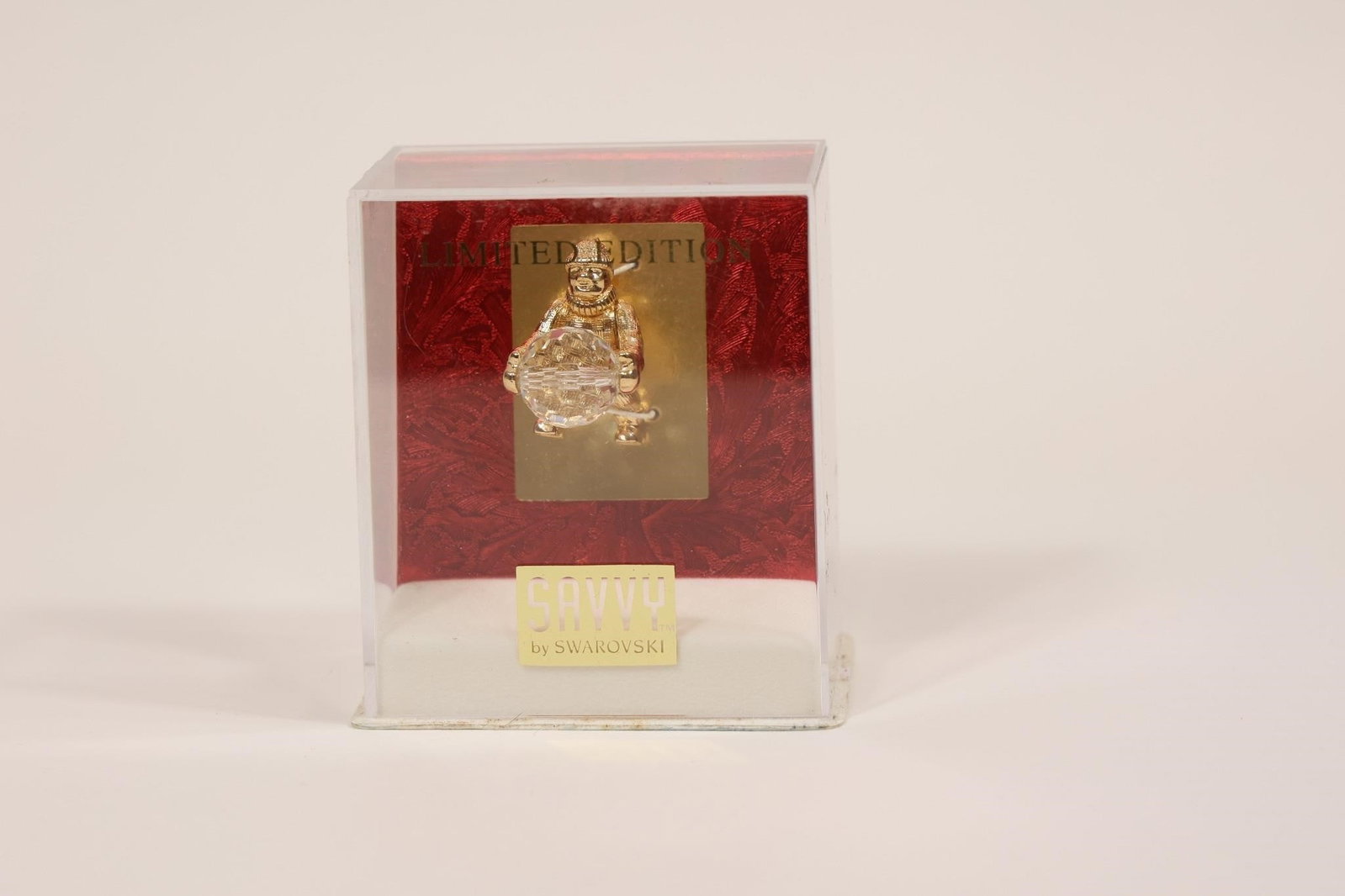 Limited Edition Swarovski Figure in Red Box: Decorative brooch featuring a figure holding a large crystal centerpiece, presented in a red gift box marked "LIMITED EDITION"; likely a collectible costume jewelry piece, possibly Swarovski-related,