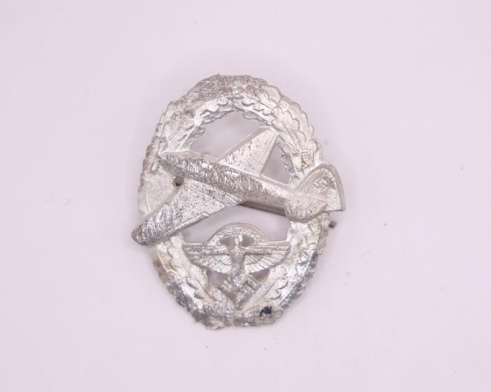 German NSFK Motor Pilot's Badge: NSFK (National Socialist Flyers Corps) Motor Pilot's Badge, featuring the classic winged design associated with the organization. Constructed in a silvered zinc style with detailed craftsmanship and