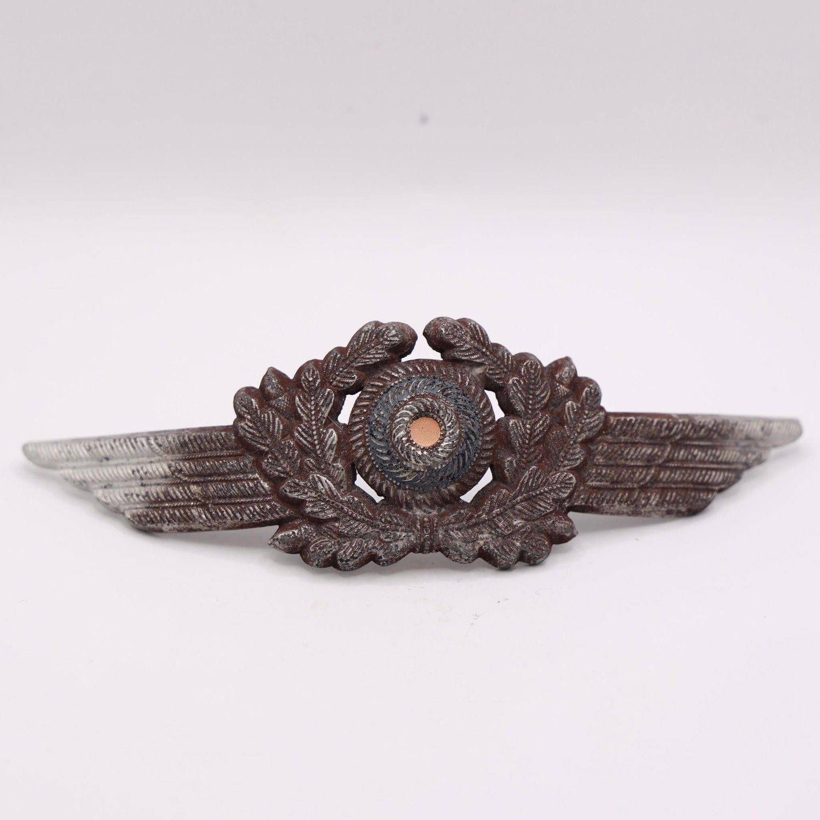 WWII German Luftwaffe Visor Cap Wreath & Cockade: Original WWII Luftwaffe visor cap wreath and tri-color cockade, silver-washed aluminum, detailed winged oak-leaf design, prongs intact, good used condition.