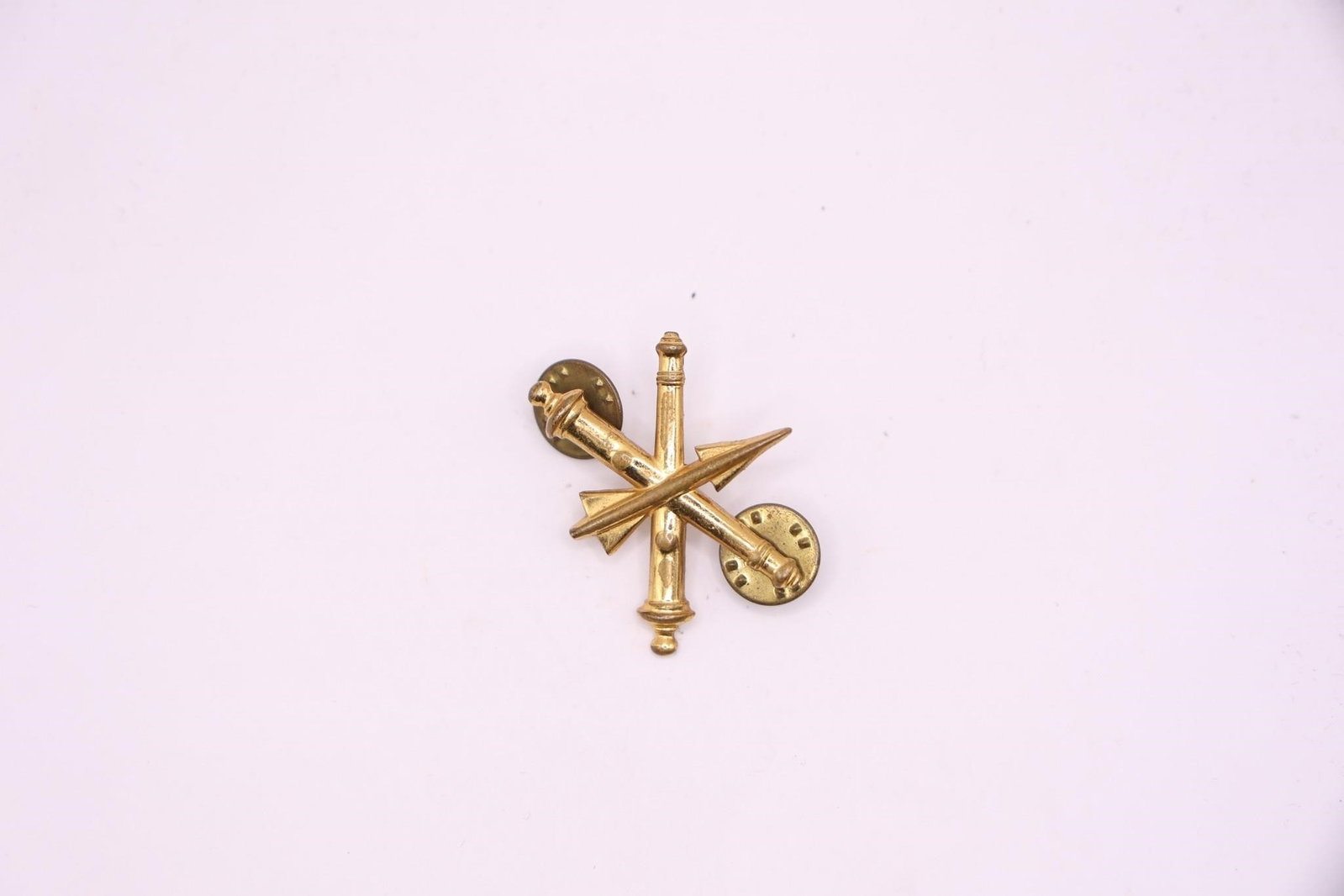 US Army Air Defense Artillery Branch Insignia: It features a missile surmounting two crossed field guns, all in gold-colored metal. The insignia has been in use since 1957, with the Air Defense Artillery established as a basic branch in 1968. It