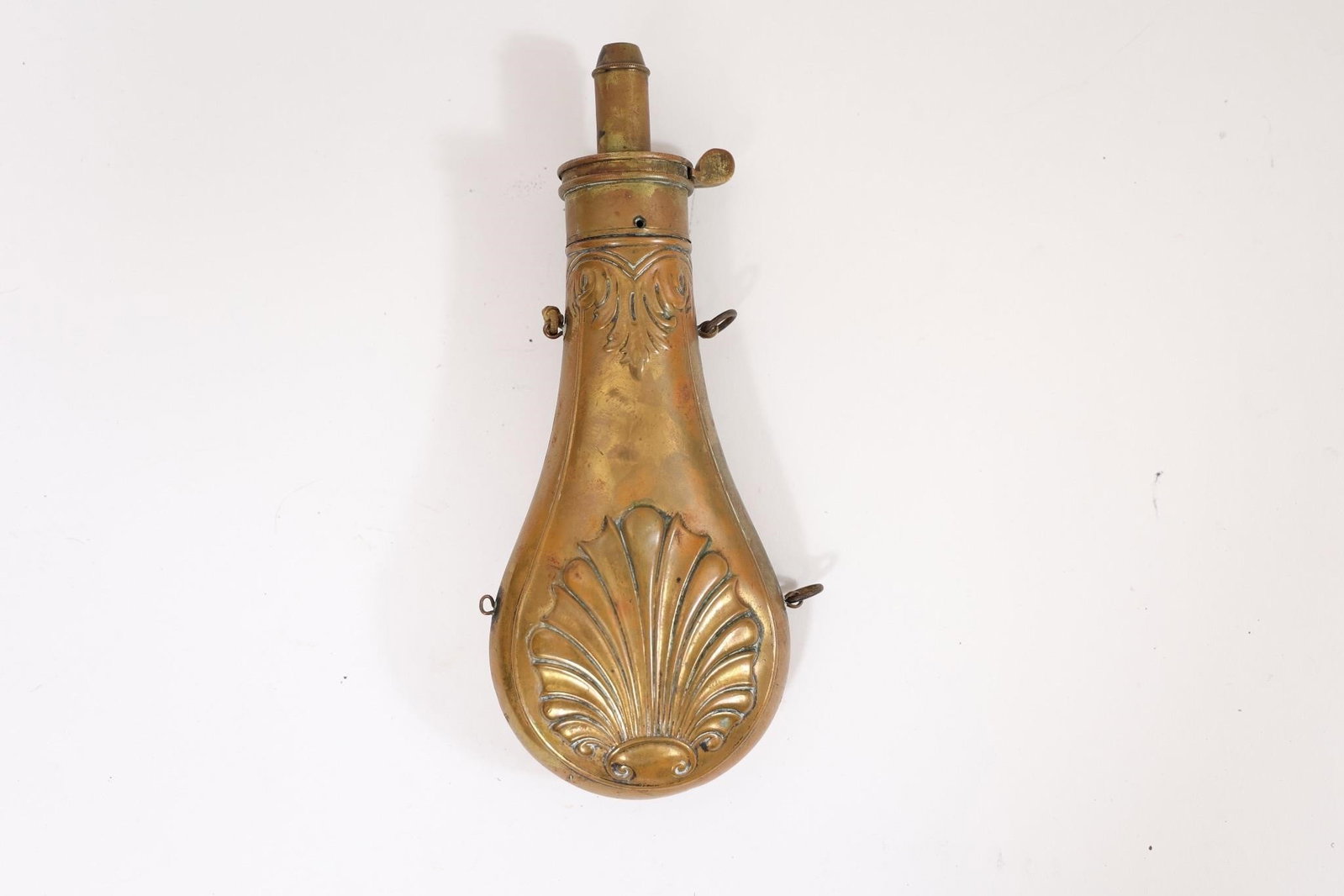 Early Brass Powder Flasks: Early brass powder flasks, traditionally used for carrying gunpowder. Featuring embossed decorative designs and classic antique form. Likely 19th century examples with natural patina from age and