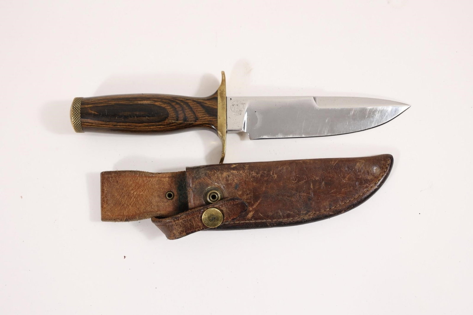 S&W Model 6030 Survival Knife W/ Sheath: Smith & Wesson model 6030 Bowie-style survival knife featuring a 5-1/2" blade and 10" overall length. Includes laminated wood handle with storage compartment and leather sheath. Shows light wear consi
