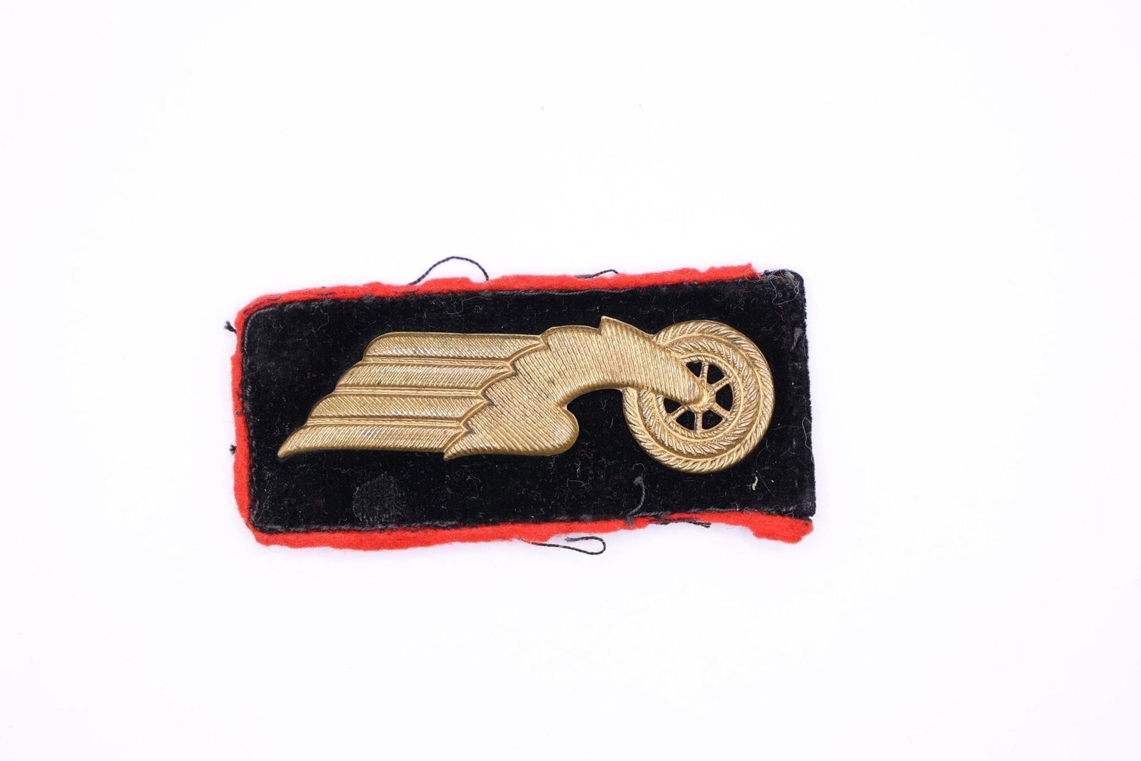 German Reichsbahn Collar Tab (First Pattern): German Reichsbahn first pattern collar tab (circa 1933), black velvet with red wool piping, stamped alloy winged wheel emblem, tan buckram backing.