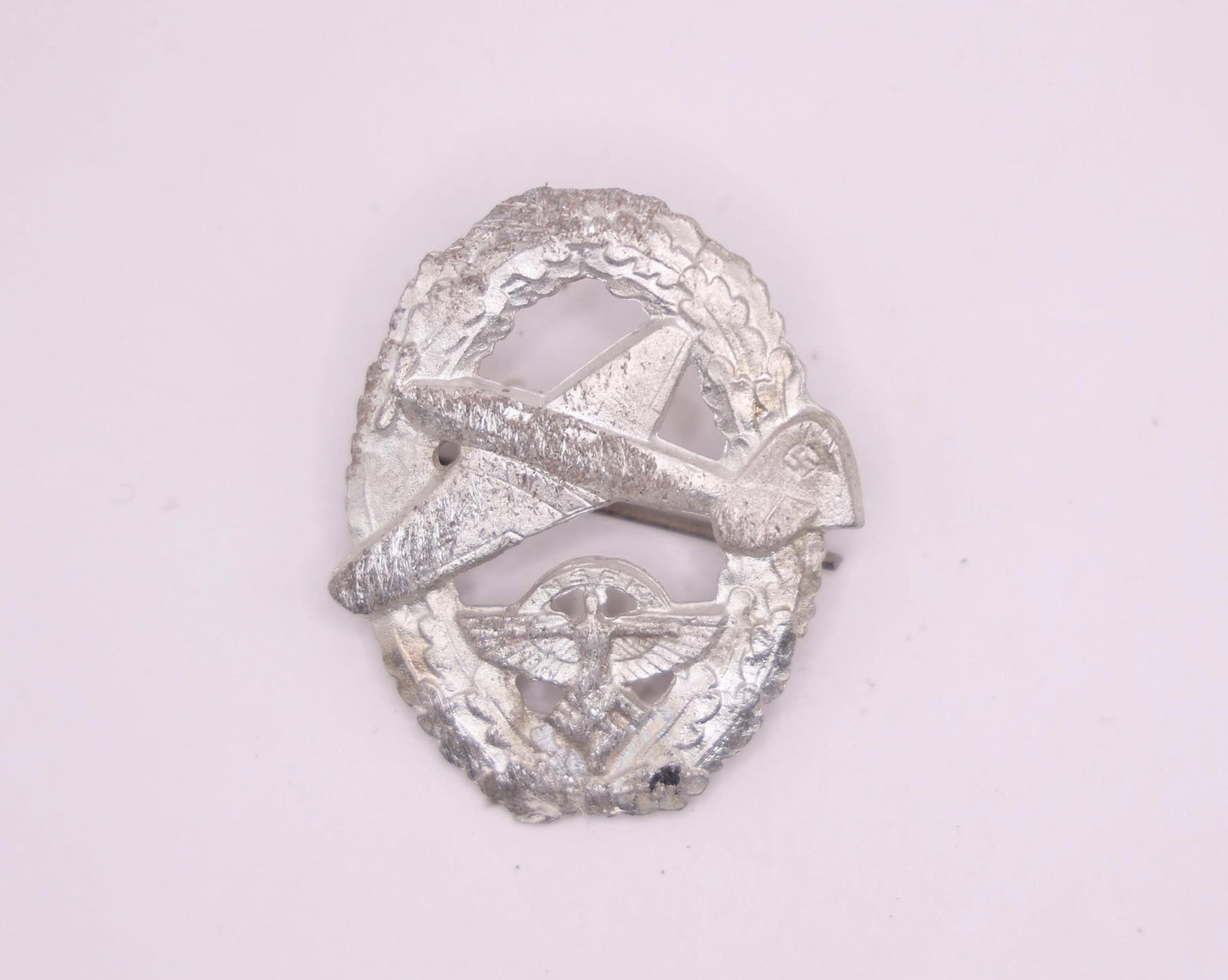 German NSFK Motor Pilot's Badge: NSFK (National Socialist Flyers Corps) Motor Pilot's Badge, featuring the classic winged design associated with the organization. Constructed in a silvered zinc style with detailed craftsmanship and