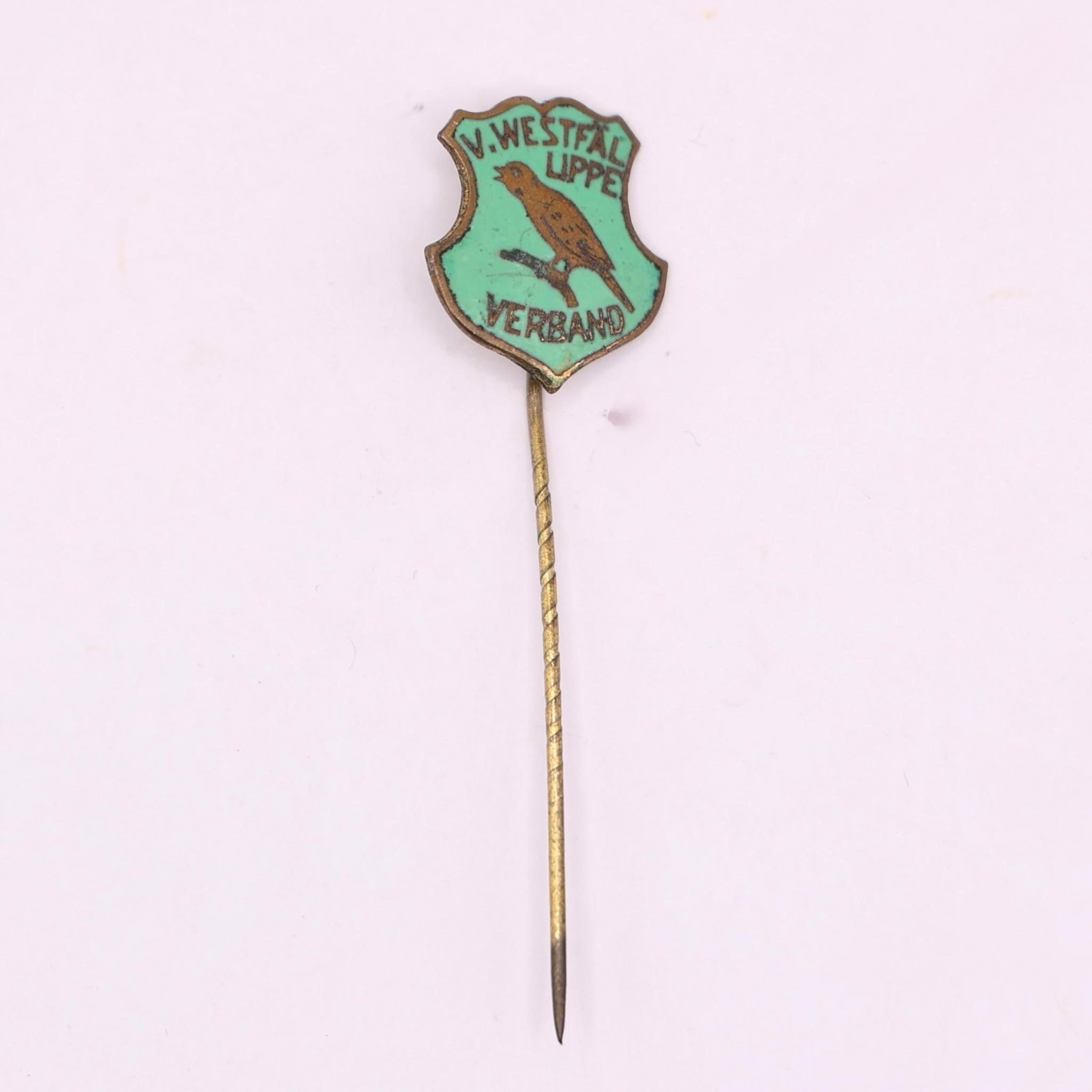 Vintage V. Westfal Lippe Verband Enamel Stick Pin: A small vintage enamel stick pin with a shield-shaped badge at the top. It has a light turquoise background, a brown bird perched on a branch in the center, and black text reading "V. WESTFAL LIPPE" a