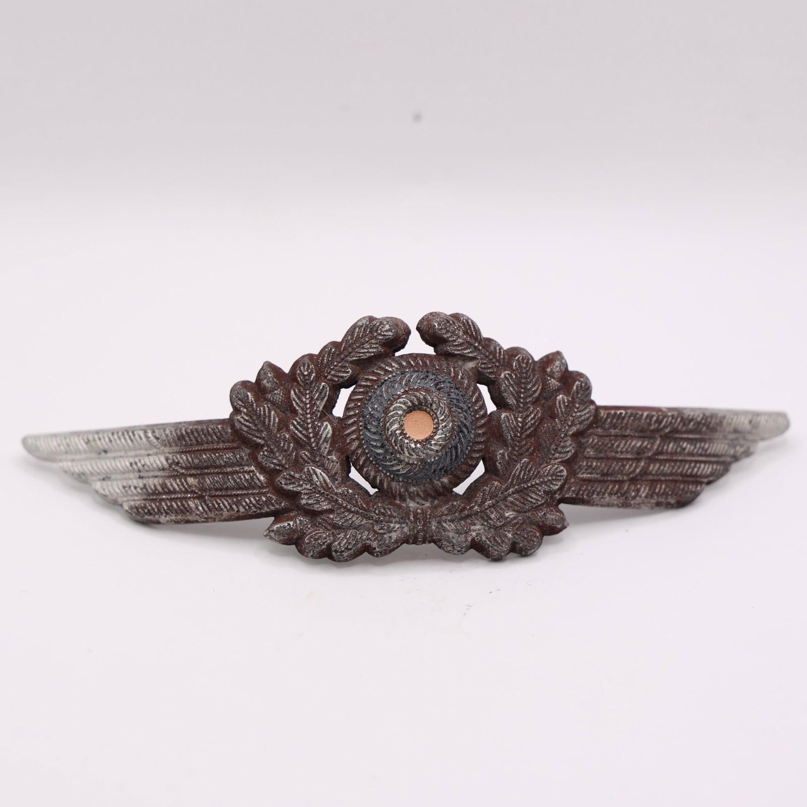 WWII German Luftwaffe Visor Cap Wreath & Cockade: WWII Luftwaffe visor cap wreath and tri-color cockade, silver-washed aluminum, detailed winged oak-leaf design, prongs intact, good used condition.