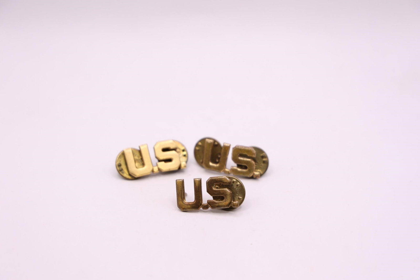 Vintage U.S. Army officer collar insignia pins: These are These are vintage US Army officer collar insignia pins. They feature the letters "U.S." in gold or brass finish. The pins are typically worn on the uniform collar. They are from the World Wa