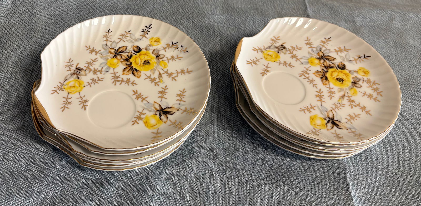 Vintage (ca. 1950s) Japanese Yamaka Shell Shaped Snack plates x12 - Pattern M7L1 Melasco: This lot features 12x vintage Japanese Yamaka shell-shaped snack plates, pattern M7L1 by Melasco, decorated with yellow roses, gray/brown leaves, and intricate gold trim around the rim. The plates fea