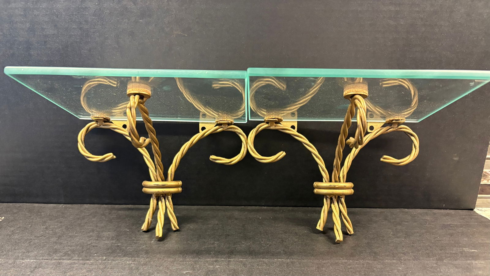 MCM Pair of Vintage Hollywood Regency Gold Tone Metal w/Clear Glass Shelf Inserts: This lot features a pair of vintage Hollywood Regency Gold Tone Metal w/clear glass shelf inserts. The metal "brackets" feature a distinctive twisted rope design. They function as decorative wall moun