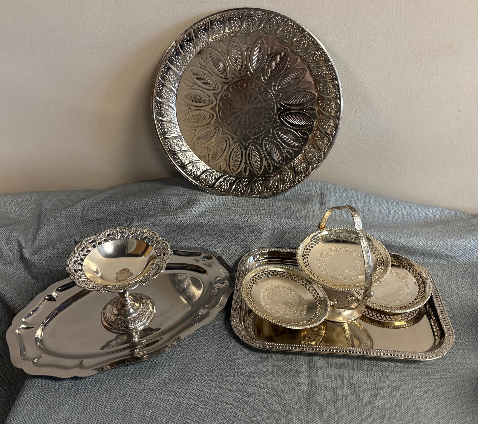 Vintage 5-Piece Collection of Silver-Plated Tableware: This 5-piece collection of silver-colored tableware includes serving trays and bowls with ornate, traditional designs. They include....1). Round Ottoman-Style Tray - It features a central sunburst/sta