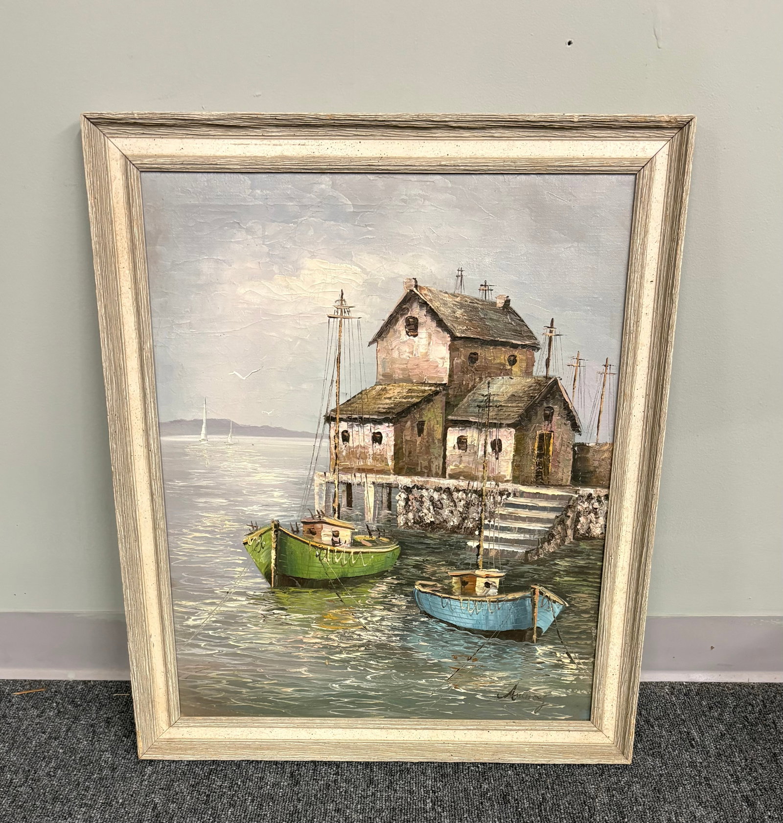 Framed Harbor Scene Oil on Canvas Painting: Framed oil on canvas painting of a harbor scene. It features a textured dock house and fishing boats. The piece utilizes a distinctive color palette with green and blue boats contrasting against the m