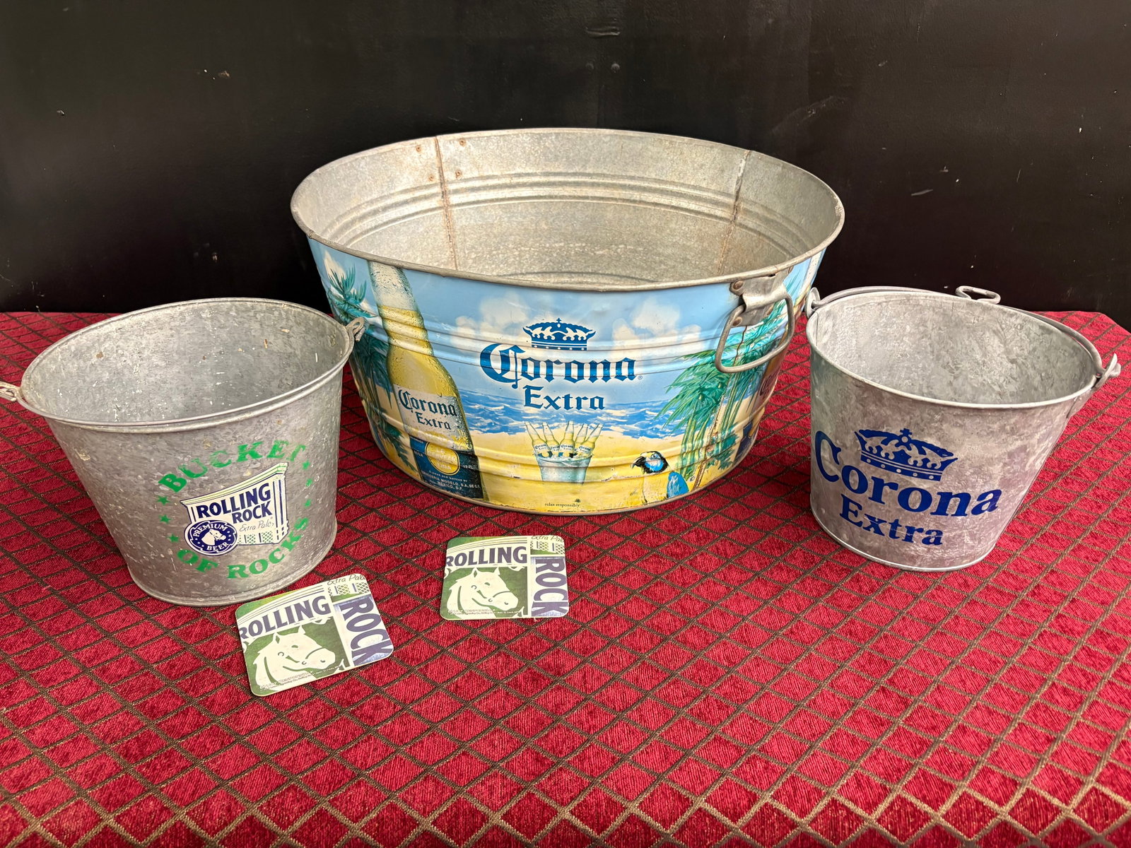 Vtg Trio of Galvanized Beer Ice Buckets + Pub Coasters/Mats - Corona & Rolling Rock: Collection of vintage galvanized metal beer ice buckets and a party tub featuring iconic branding from Corona Extra and Rolling Rock. Included is…Oversized Corona Party Tub: wrapped in a full-color 