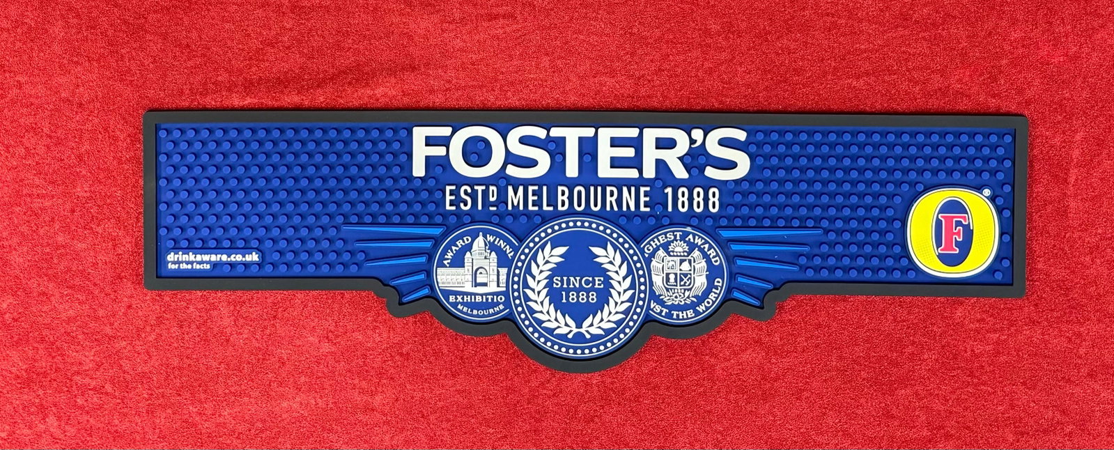 Foster’s Beer Heavy-Duty Rubber Bar Runner/Mat: Official authentic Foster’s Bar Mat, a standard commercial runner used to catch spills, protect bar surfaces, and drain glassware. It's emblazoned with the iconic Foster's logo, the founding year 18