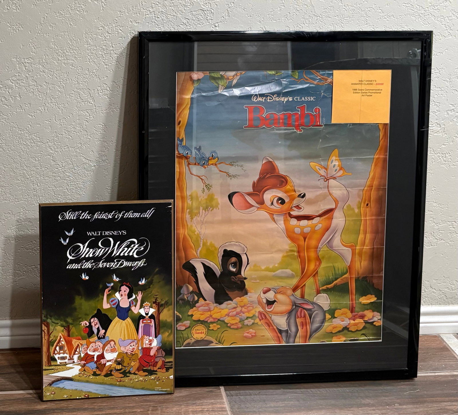 Vtg (1980s) Walt Disney’s Promotional Display Grouping: A pair of Walt Disney classic promotional poster & plaque. The two pieces include...1). Vintage 1988 Classic Bambi Framed Promotional Art Poster - Released as part of a Sears Commemorative Edition Ser