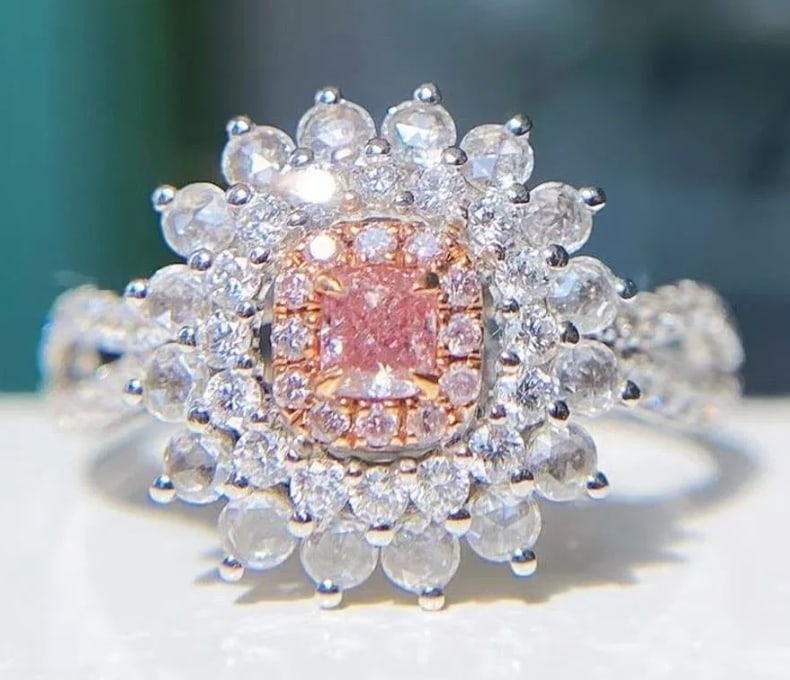 Natural Pink Diamond 18K Gold Ring: Estimate $5,800-$9,50018K gold deluxe inlaid with 0.15ct natural pink diamond, matched with 0.72ct natural diamonds. Shining and dazzling, bright color, good clarity. Shape: Cushion-shaped. Cut: Excel