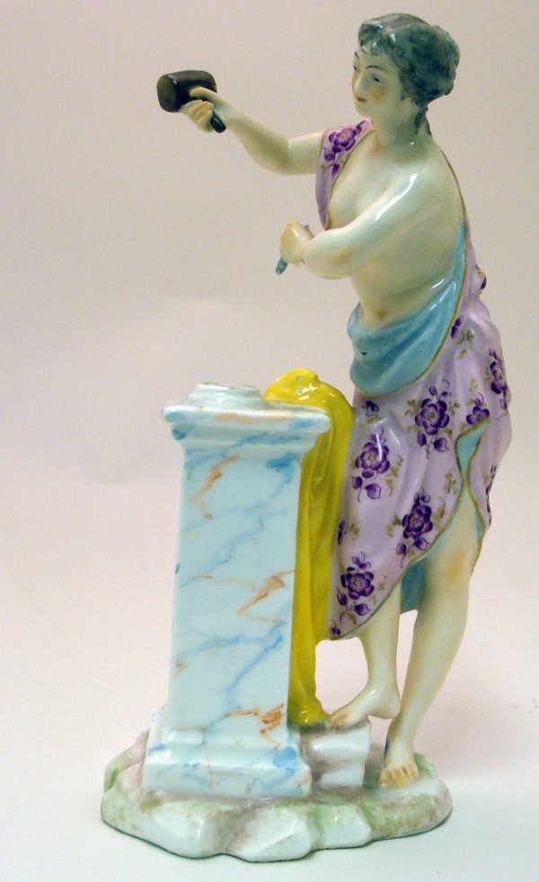 Meissen Porcelain Figurine: Meissen Porcelain Figurine. Figure is of a bare chested women standing over a podium with a chisel in one hand and mallet in the other. Signed with crossed swords on the base. Measures 8 inches in hei